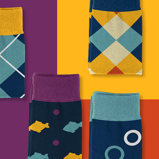 Colorful socks with multiple designs folded and arranged on a multicolor background - Goldie Socks